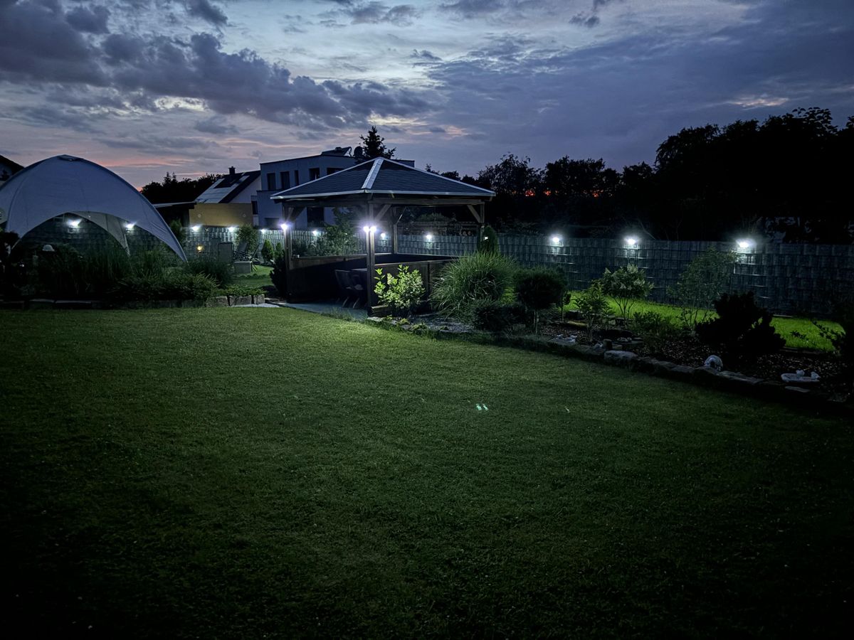 Garten in der Abenddämmerung mit beleuchteten Wegen