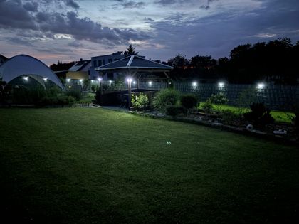 Garten in der Abenddämmerung mit beleuchteten Wegen