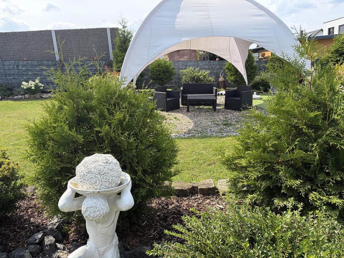 Blick durch die Hecke auf die Lounge-Ecke im Garten