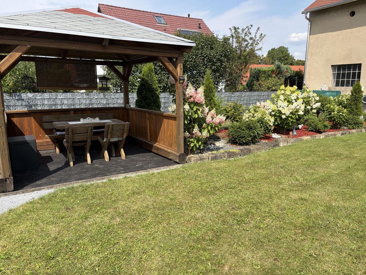 Holzpavillon umgeben von blühenden Hortensien