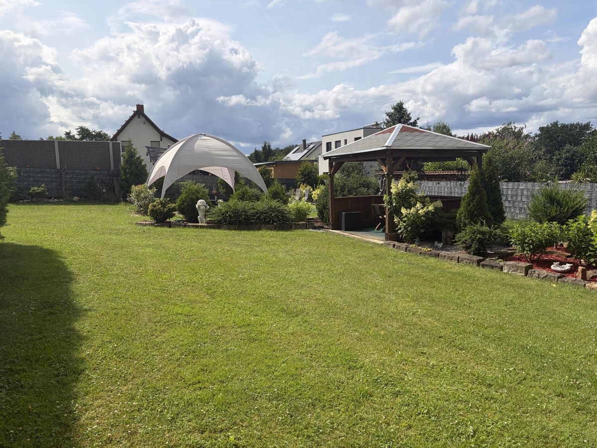 Weitläufiger Rasen mit Pavillonzelt und Holzpavillon