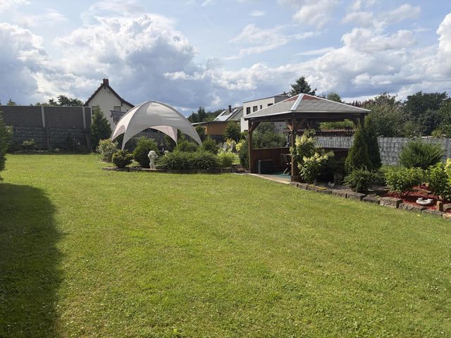 Weitläufiger Rasen mit Pavillonzelt und Holzpavillon